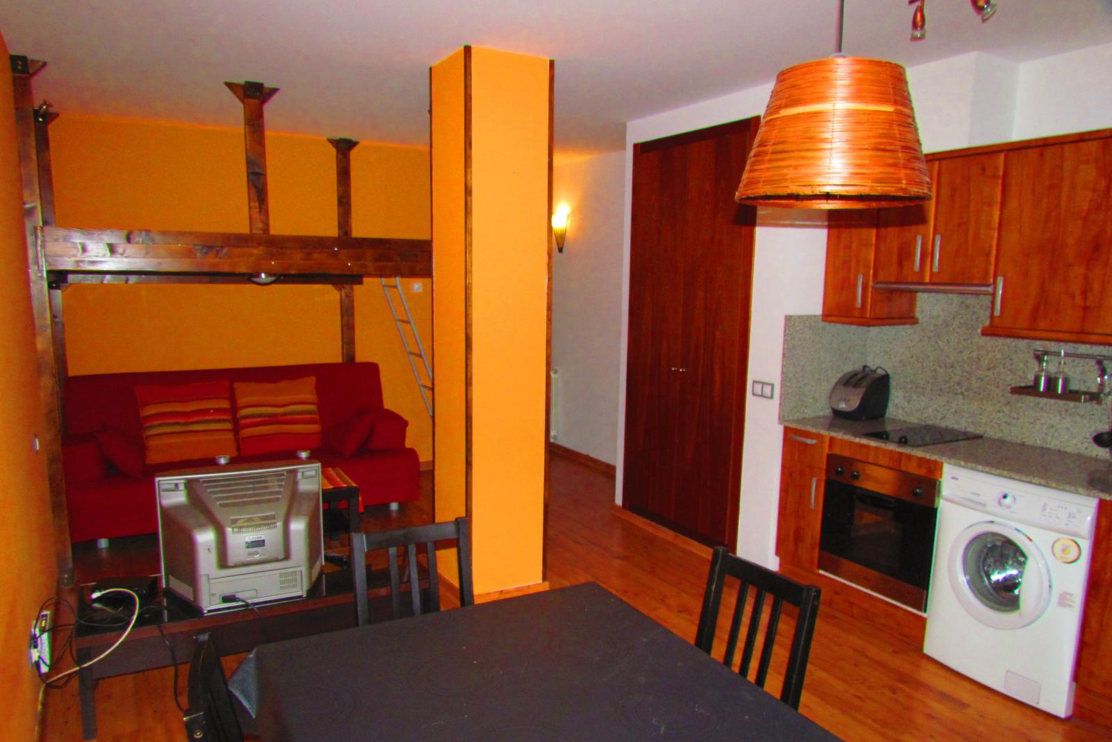 Menjador d'un apartament de muntanya abans del home staging: parets taronja, sofà vermell